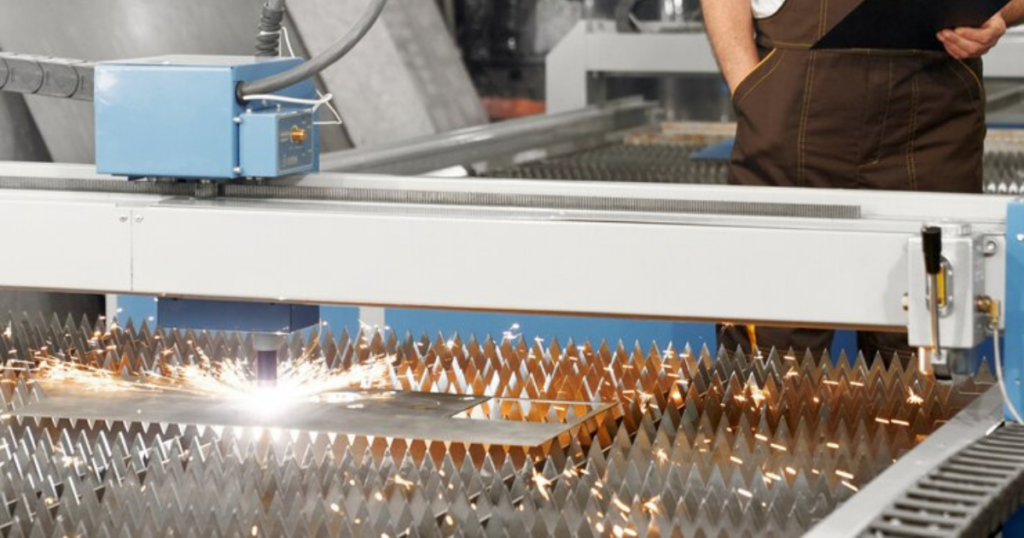 A CNC laser cutting machine emitting sparks while working on metal sheets.